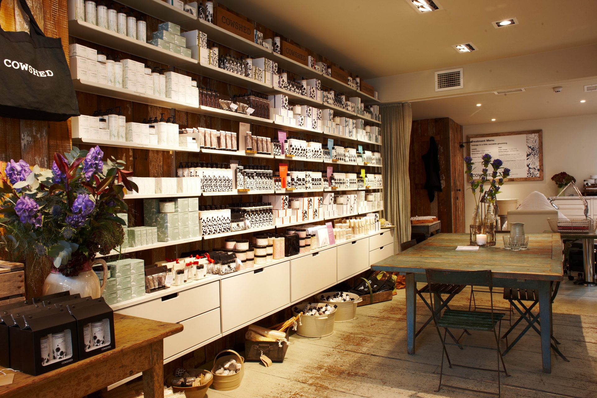 Shop display shelving at Cowshed, beauty products. Off-white metal shelves and cabinets, wall mounted. Vitsœ 606 Universal Modular Shelving System. Design Dieter Rams