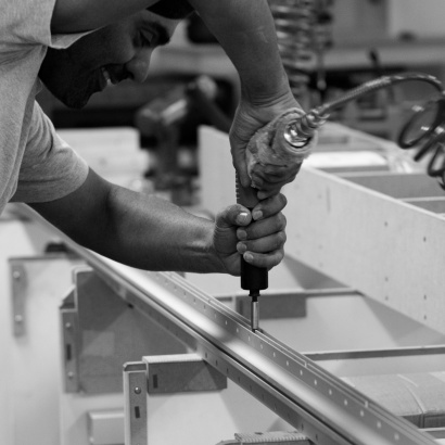 A Vitsœ workshop assistant fixing an E-Track to an X-Post for the 606 Universal Shelving System