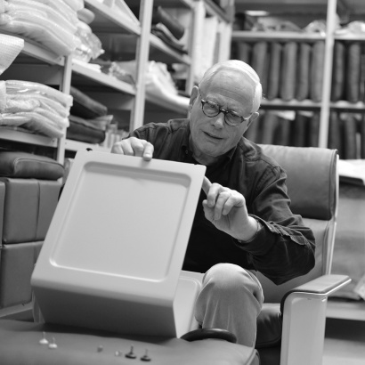 Dieter Rams sit on a 620 Chair inspecting the adjustable feet in the 621 Side Table.