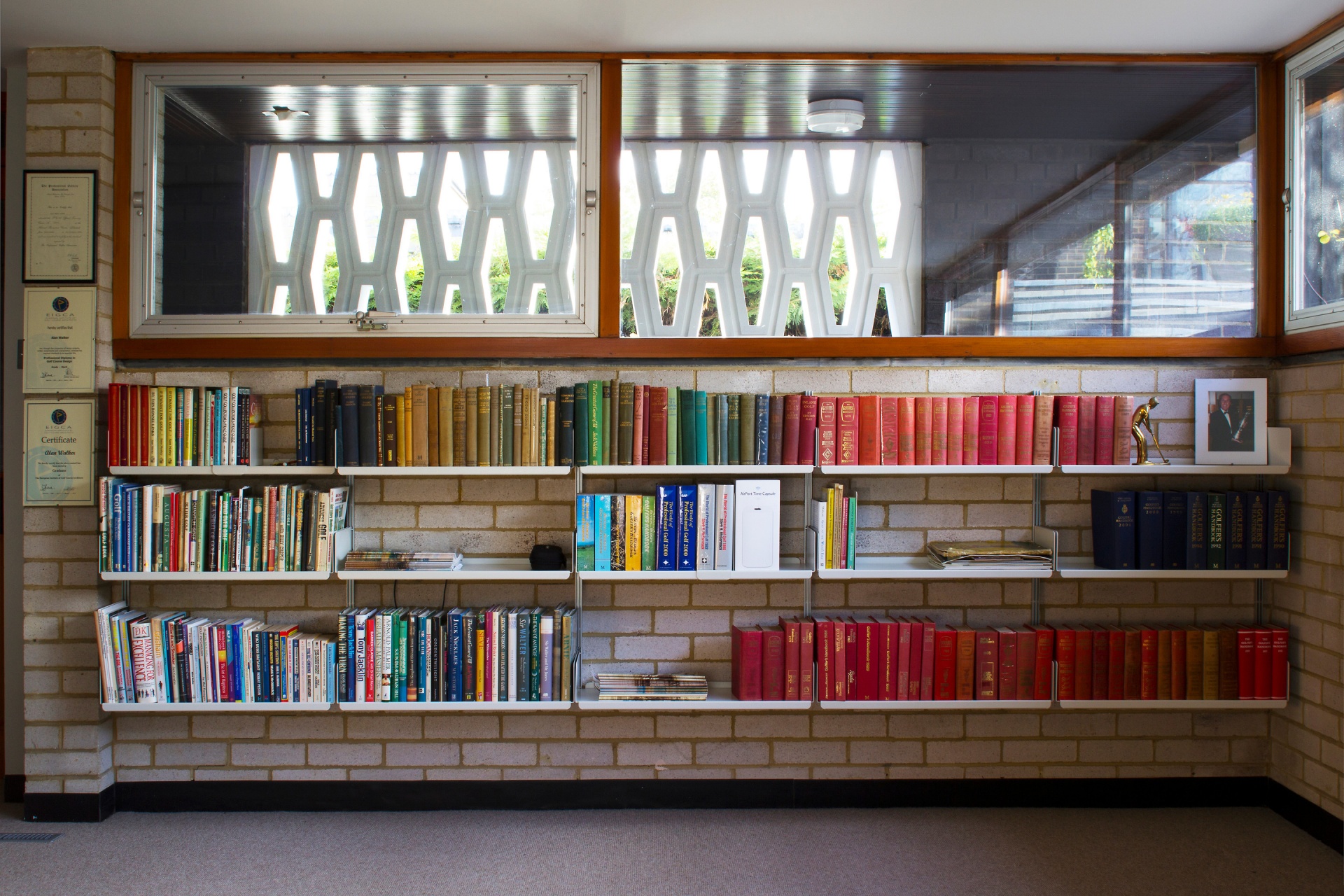 Low bookshelves, wall-mounted, white metal. Under window. Custom solutions for book storage. Designer shelves, Dieter Rams. Vitsœ 606 Universal Modular Shelving System..