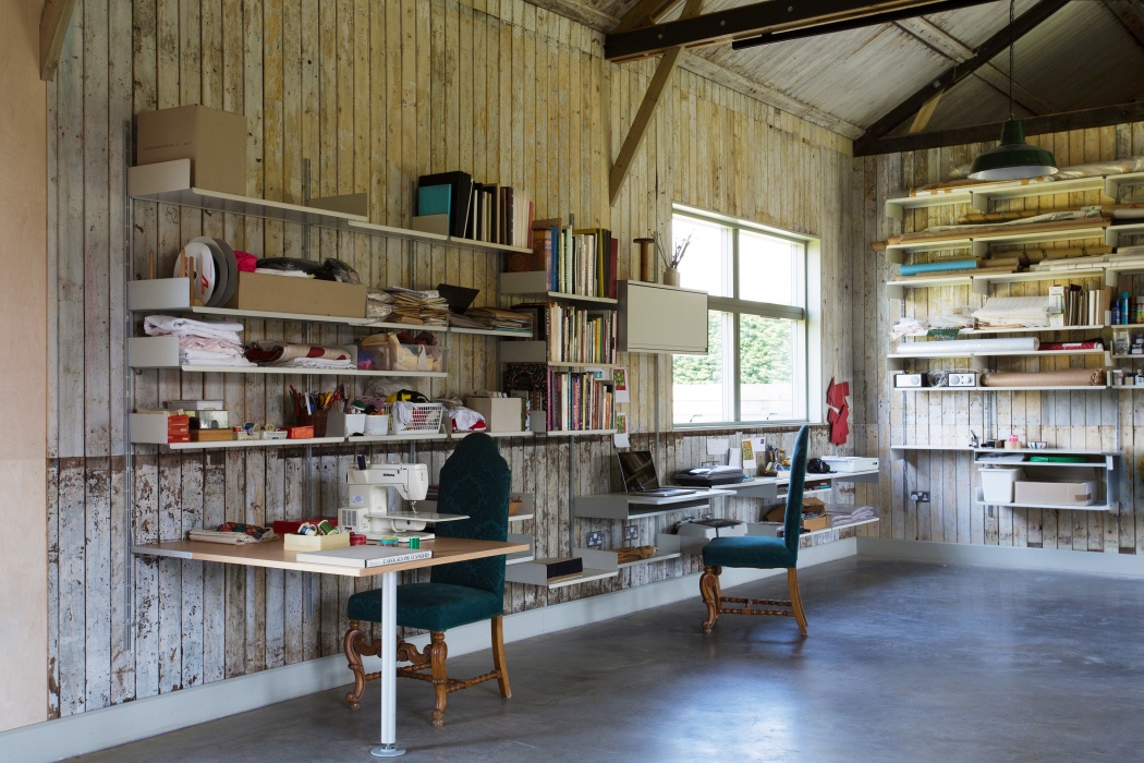 تكون المسارات غير مرئية تقريبًا عند تركيبها على الجدران الخشبية لاستوديو فنان.  ماكينة الخياطة على طاولة متكاملة  كمبيوتر محمول على رف المكتب ؛  ظلت مساحة الطوابق واضحة