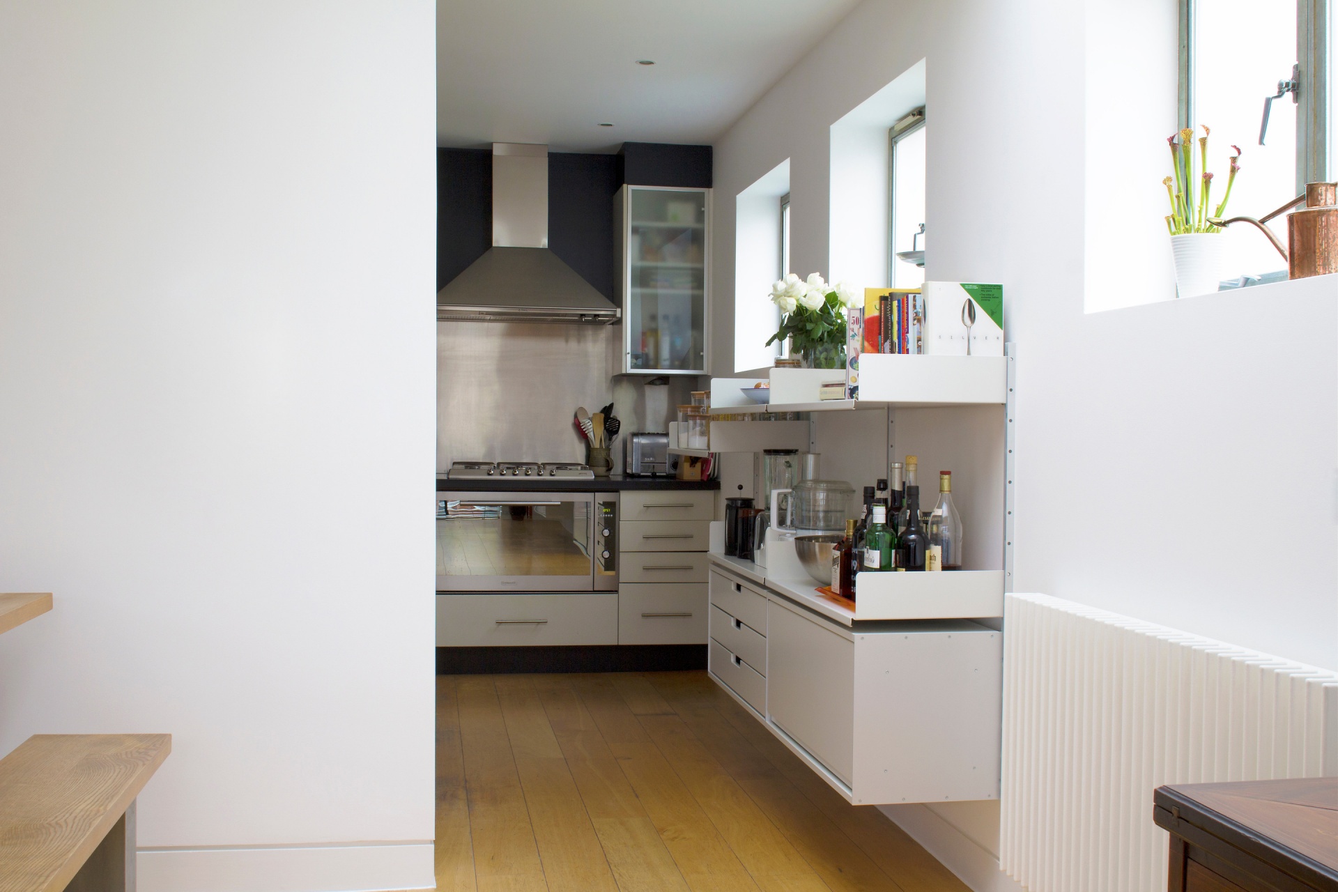 Modern kitchen bookshelf, wall mounted open shelves and cabinets, heavy kitchenware and display, recipe books. Modular Vitsœ 606 Shelving System. Designer shelves, Dieter Rams
