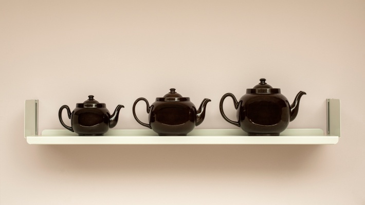 Three teapots on a Vitsœ shelf, wall-mounted.