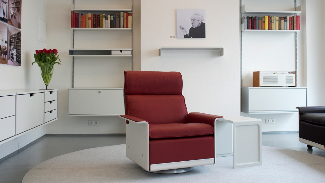 620 Chair high back in red leather with off-white shell. 606 Universal Shelving System in the background.