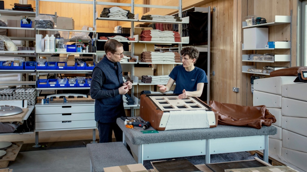 Hand-made to last, the designer lounge chair being assembled by experts at Vitsœ. Demonstration of upholstery fitting to the chair base.