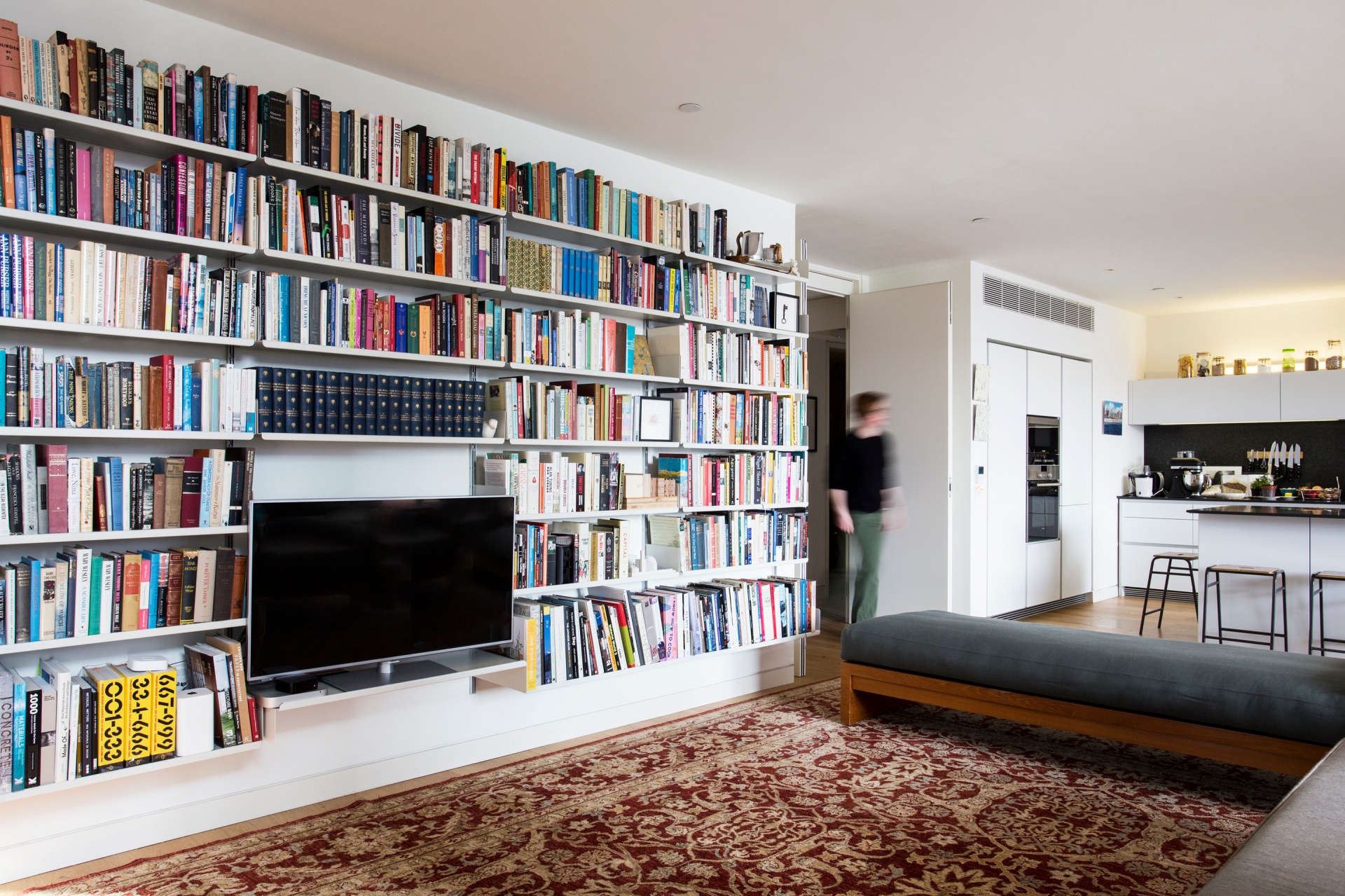 TV stand and library bookshelf for the living room. Wall mounted, off-white. Vitsœ Modular 606 Universal Shelving System. Designer shelves, Dieter Rams