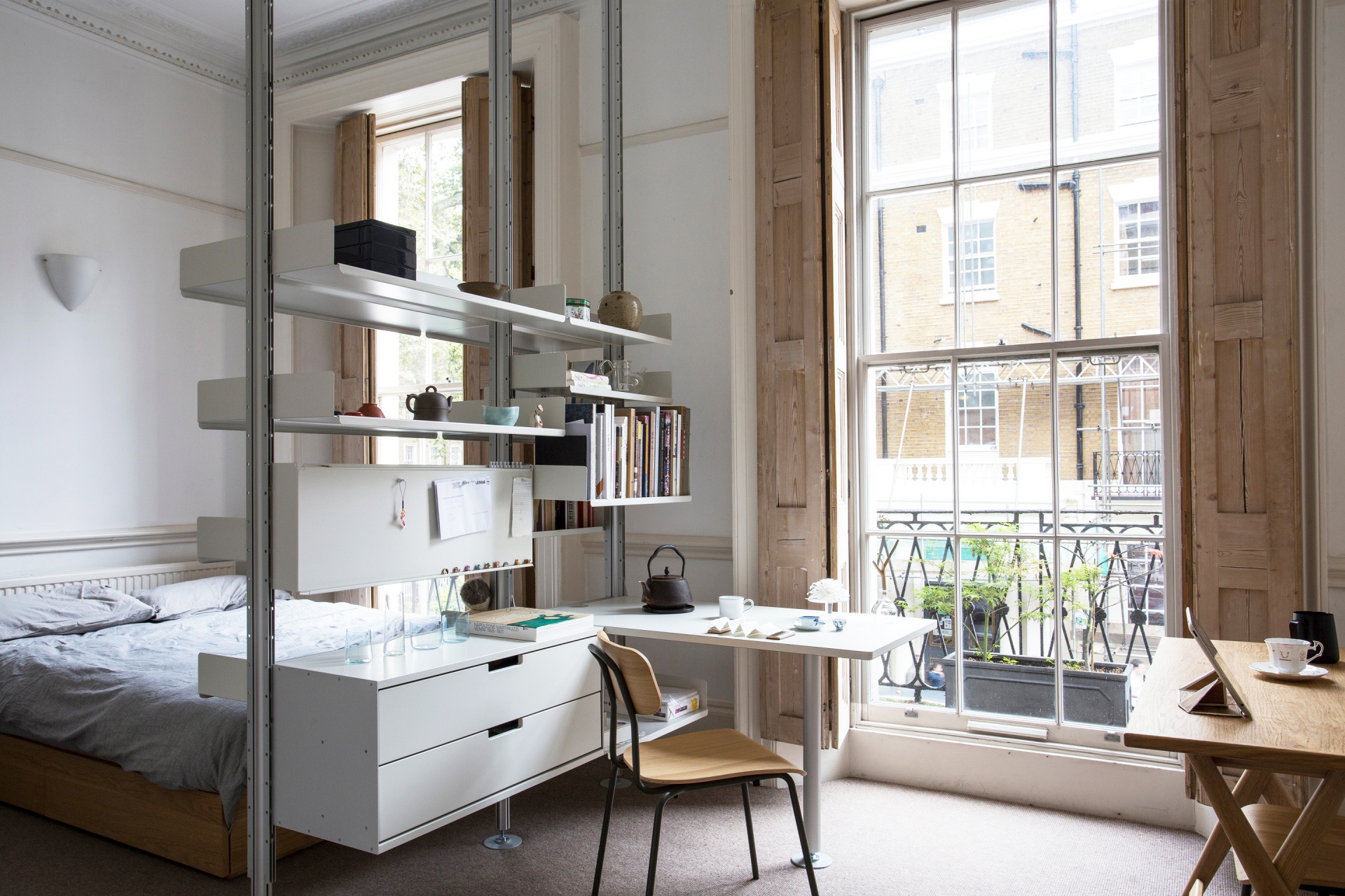 Custom made, open wardrobe shelving system with shelves and drawer cabinets. Modern floor to ceiling room divider for small apartment. Desk for workspace at home. Vitsœ modular 606 Shelving system, designer Dieter Rams.