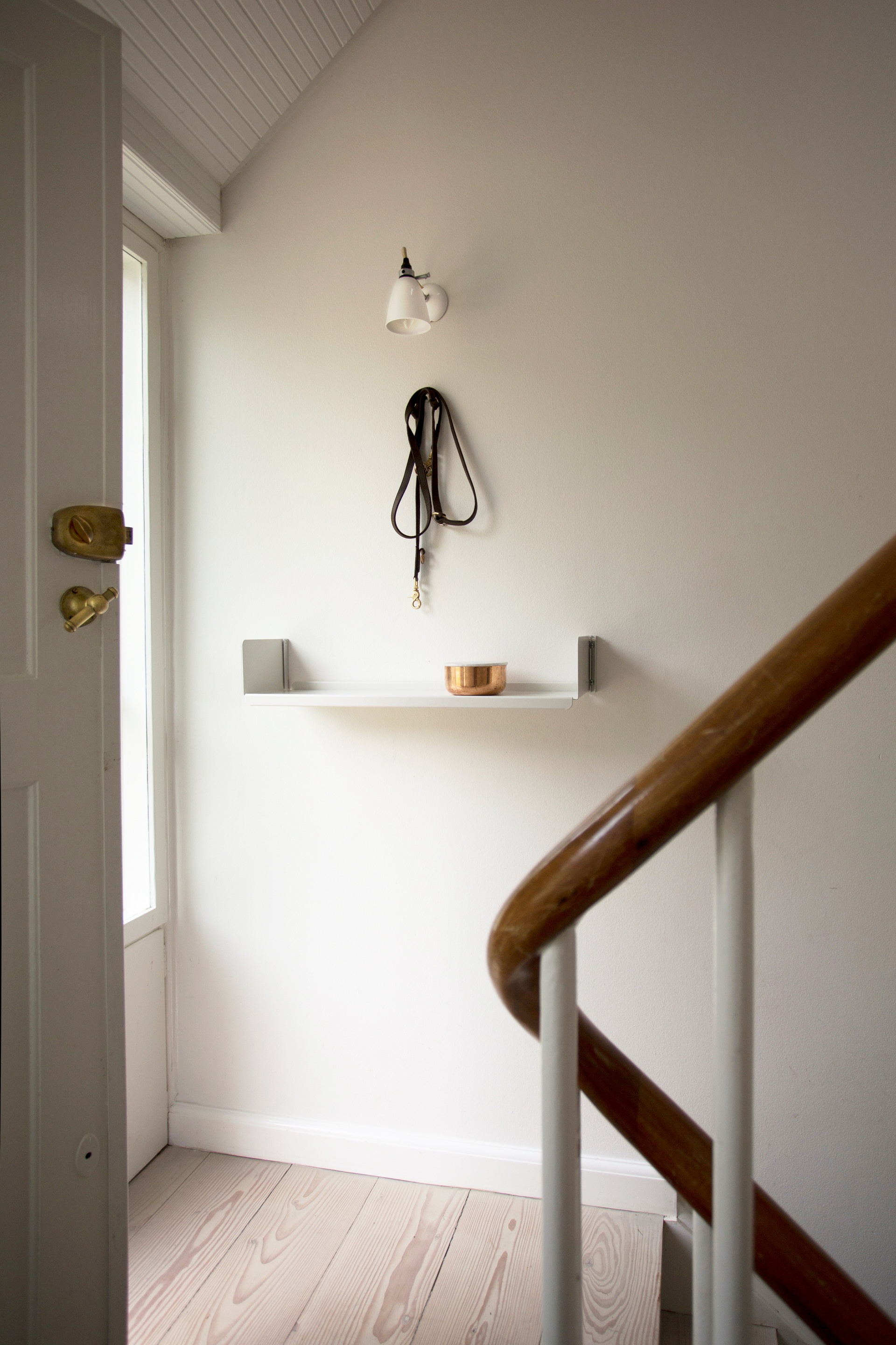 Wall mounted single shelf, off-white in landing or hallway. Vitsœ 606 modular shelving system. Designer Dieter Rams