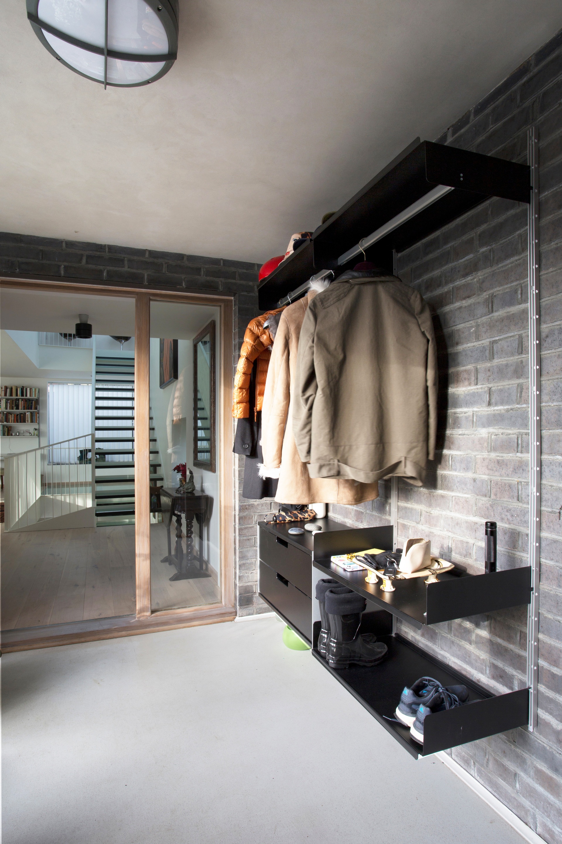 Modern minimalist open wardrobe shelving and storage in the hallway. Shoe shelf and floating drawers. Strong metal shelves with clothes rail, black. Designer, Dieter Rams. Vitsœ