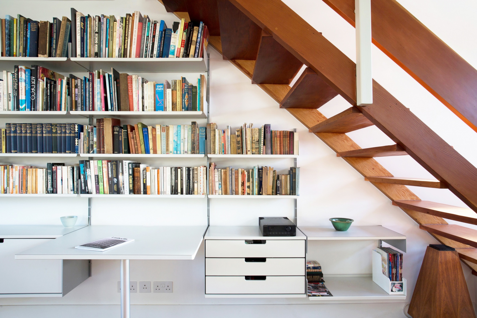 Wall mounted above desk modular shelving system 606 for home office under stairs in the hallway. Strong shelves for book collection. Wall mounted drawer cabinets. Designer Dieter Rams. Vitsœ.