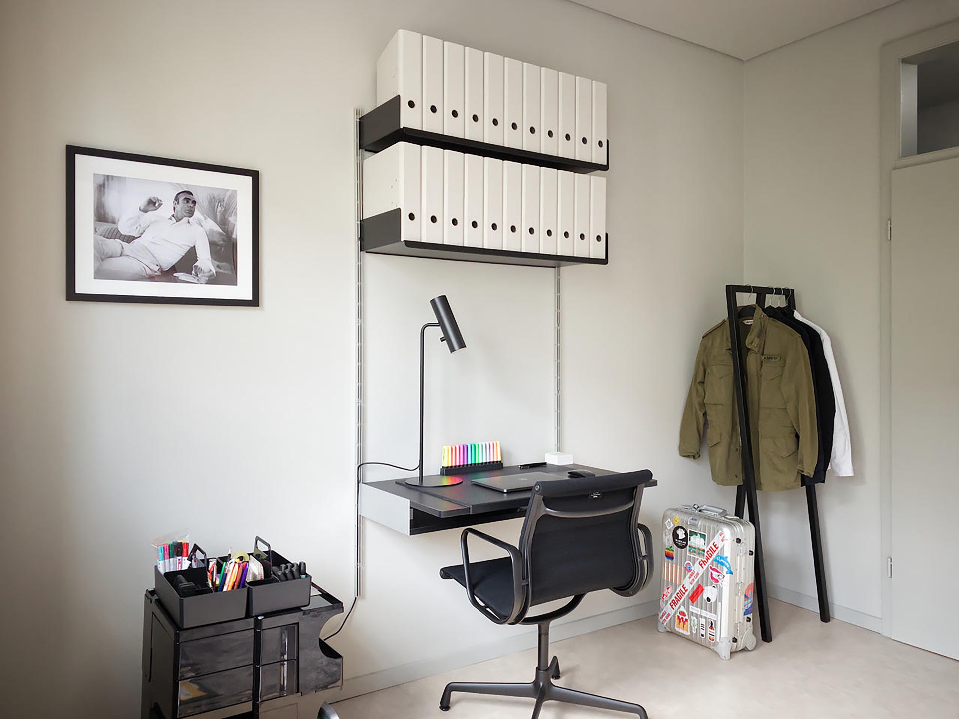 Modular shelving system with desk and strong shelves on top for box file storage. Above desk shelving unit in black, wall-mounted bookshelf, modern, minimalist home office solution for small apartment. Designer shelves, Dieter Rams. Vitsœ 606 Universal Shelving System