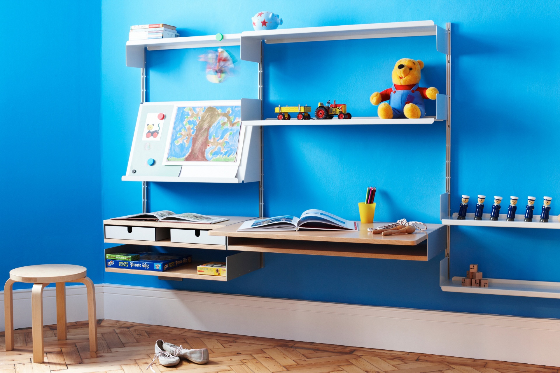 Kids desk and modular shelving system white/beech in study room. Adjustable wall mounted desk, shelving for toys and books, pencil and crayons tray, magnetic slope shelf for art display. Vitsœ 606 Universal Shelving System. Designer furniture, Dieter Rams