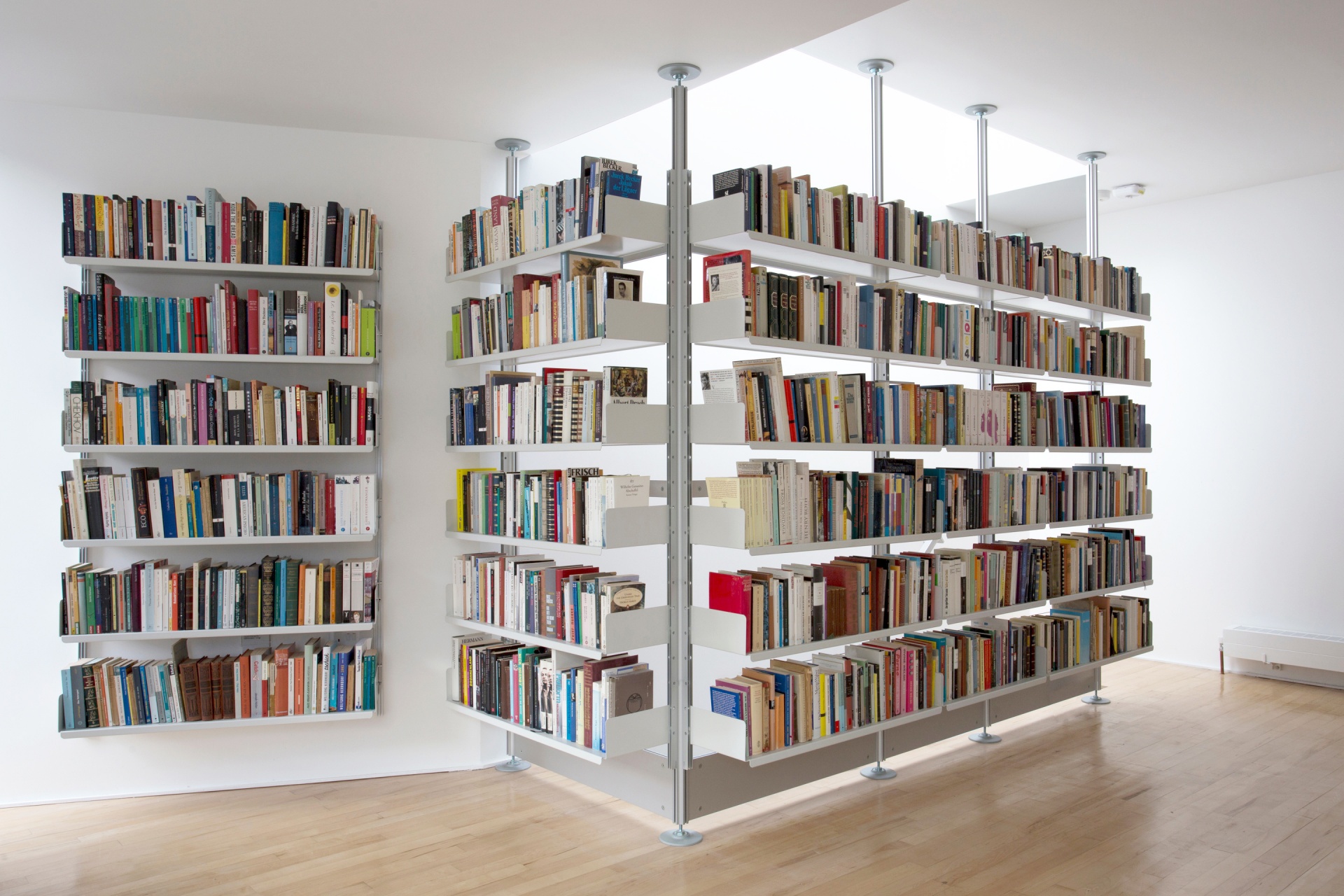Floor to ceiling bookshelves. White bespoke bookcase, compression pole system. Stairs landing. Designer shelves, Dieter Rams. Vitsœ 606 Universal Modular Shelving System.