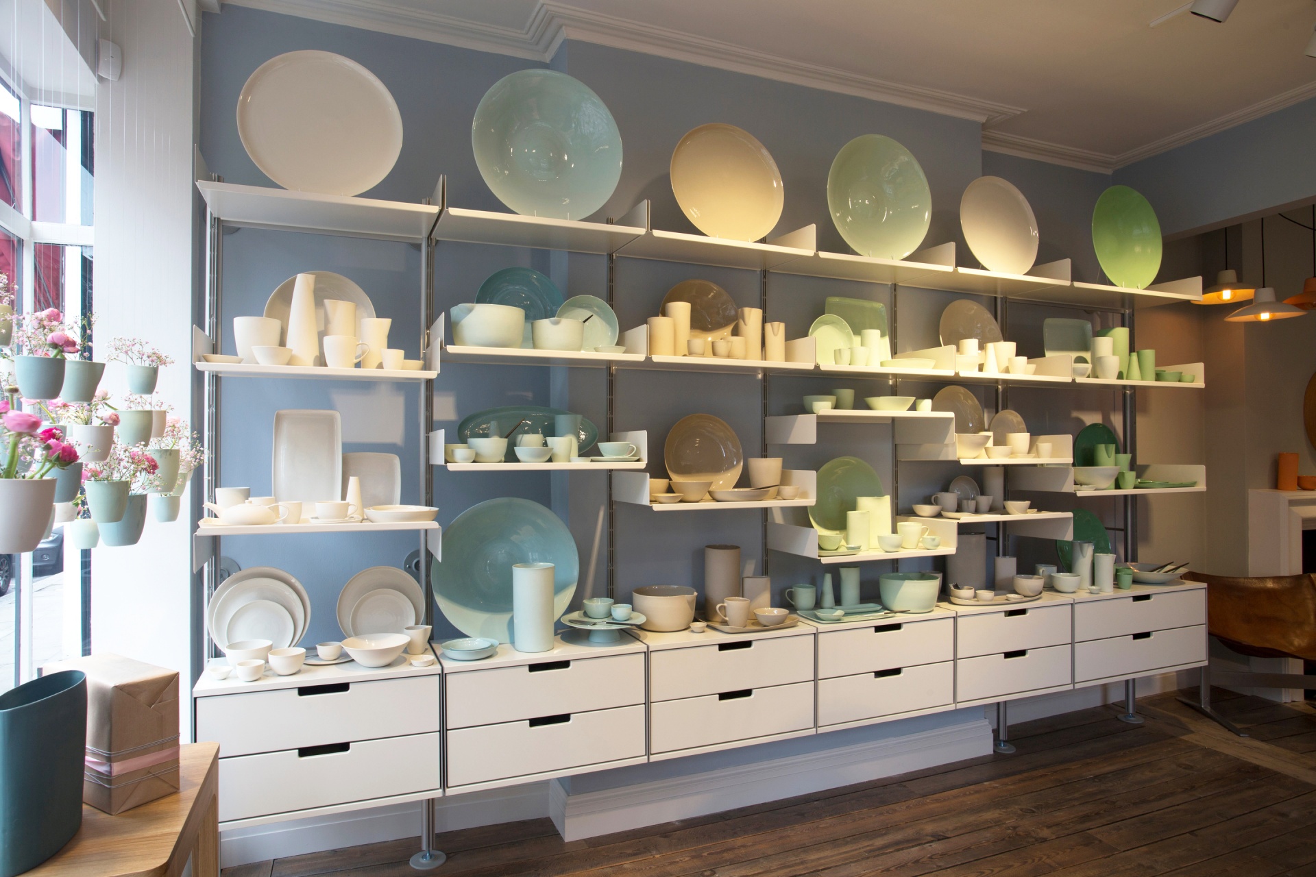 Modern store display shelving at Mud Australia. Shelves and cabinets in off-white, strong metal for heavy collections. Wall mounted. Modular Vitsœ 606 Universal Shelving System. Design Dieter Rams