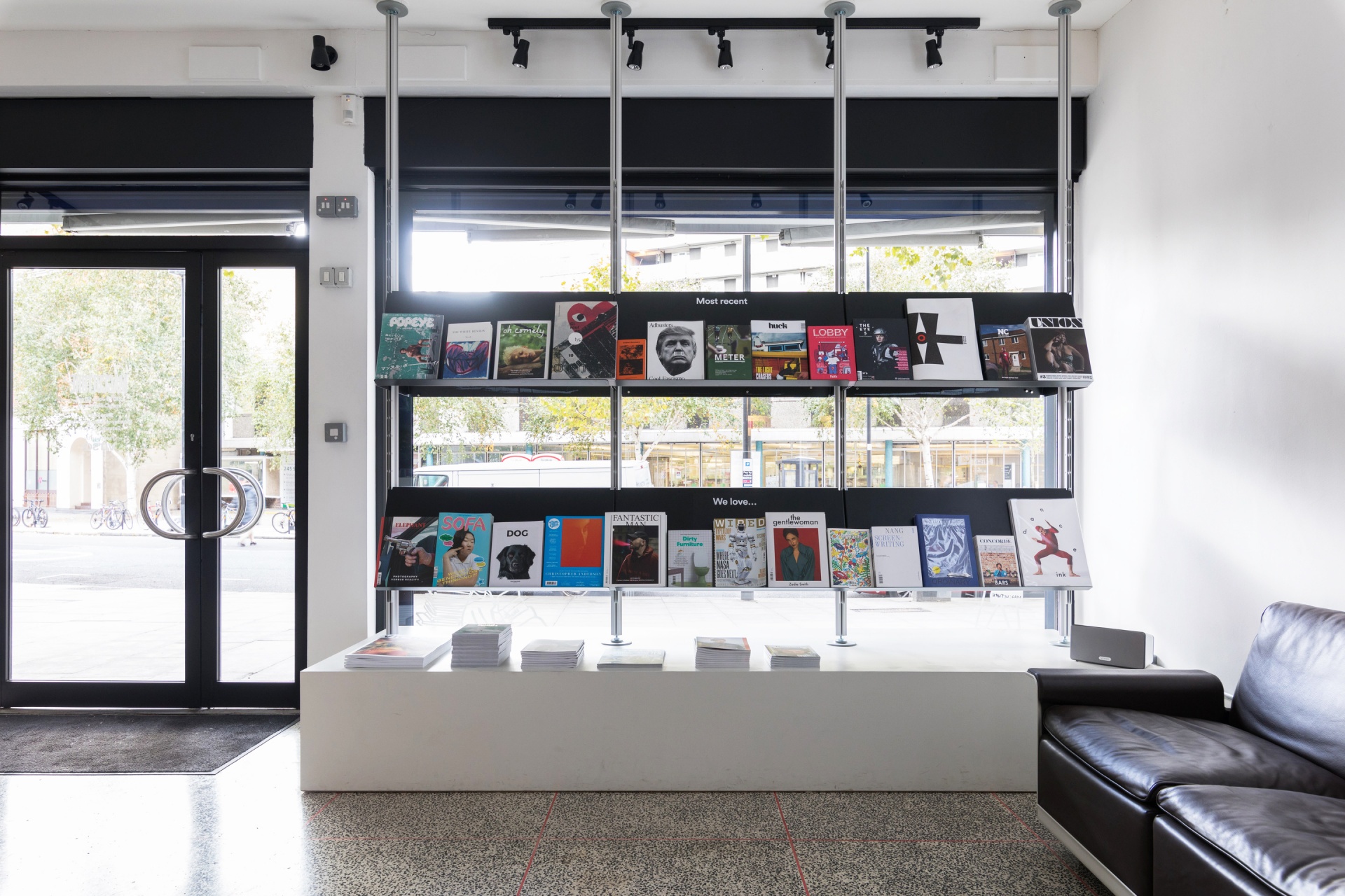 Modern shop display shelving, strong sloping shelves books. Floor to ceiling compressed system. Black metal. Two seater 620 modular sofa. Vitsœ 606 Universal Modular Shelving System. Design Dieter Rams