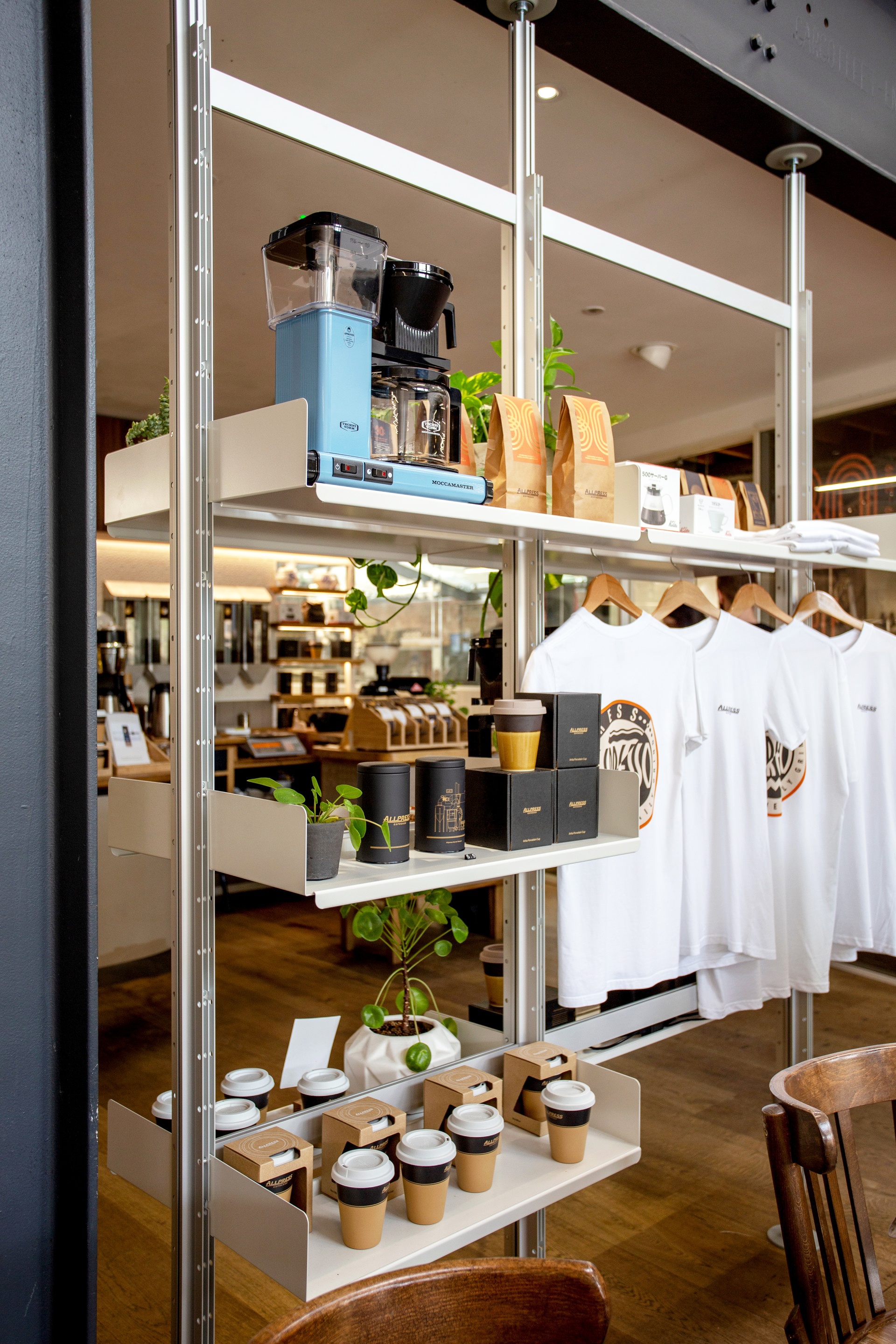 Coffee shop display shelving. Floor to ceiling compressed system used as room divider. Hanging rail shelves for clothes. Vitsœ 606 Universal Modular Shelving System. Design Dieter Rams