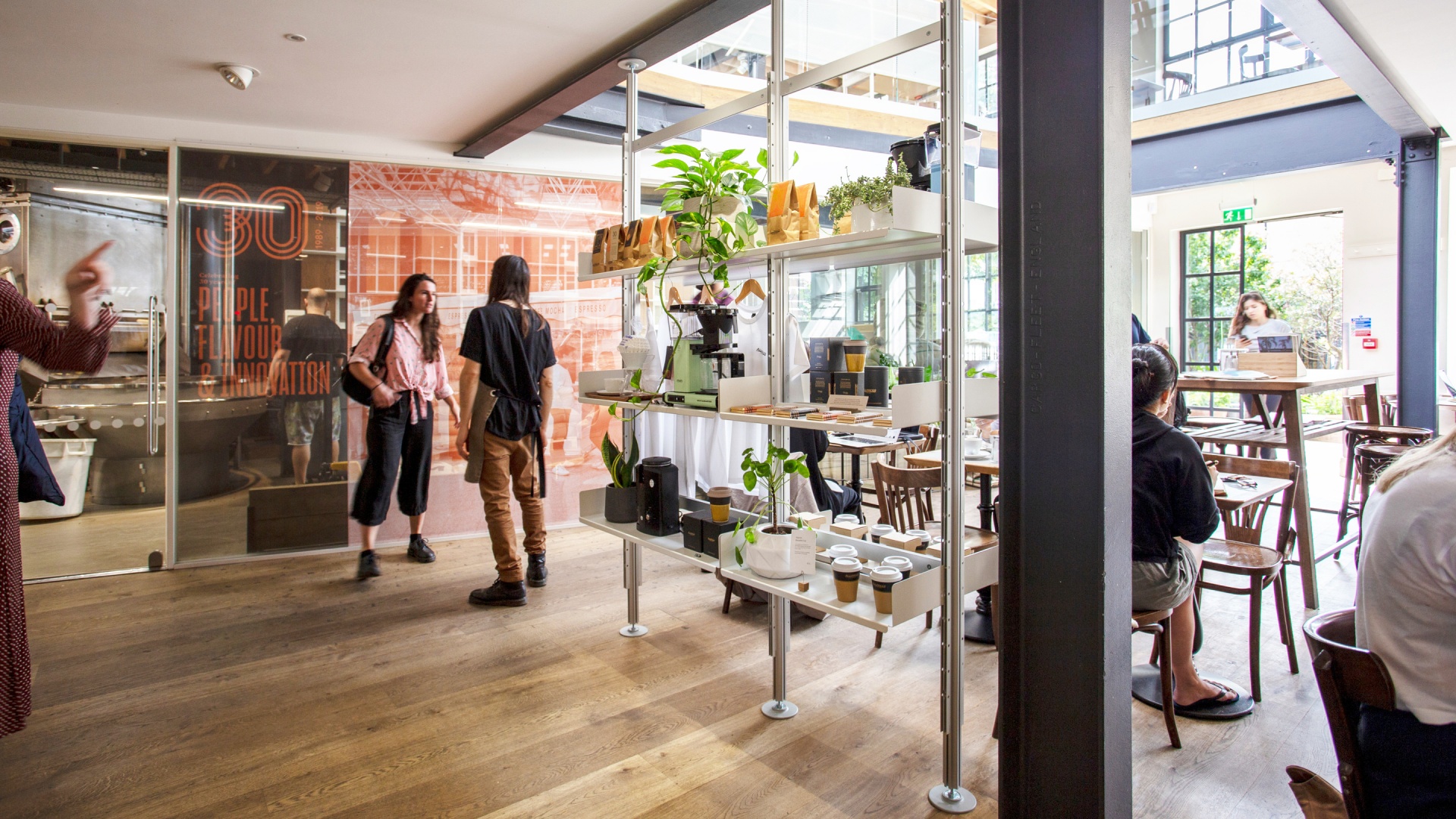 Coffee shop display shelving. Floor to ceiling compressed system used as room divider. Hanging rail shelves for clothes. Vitsœ 606 Universal Modular Shelving System. Design Dieter Rams