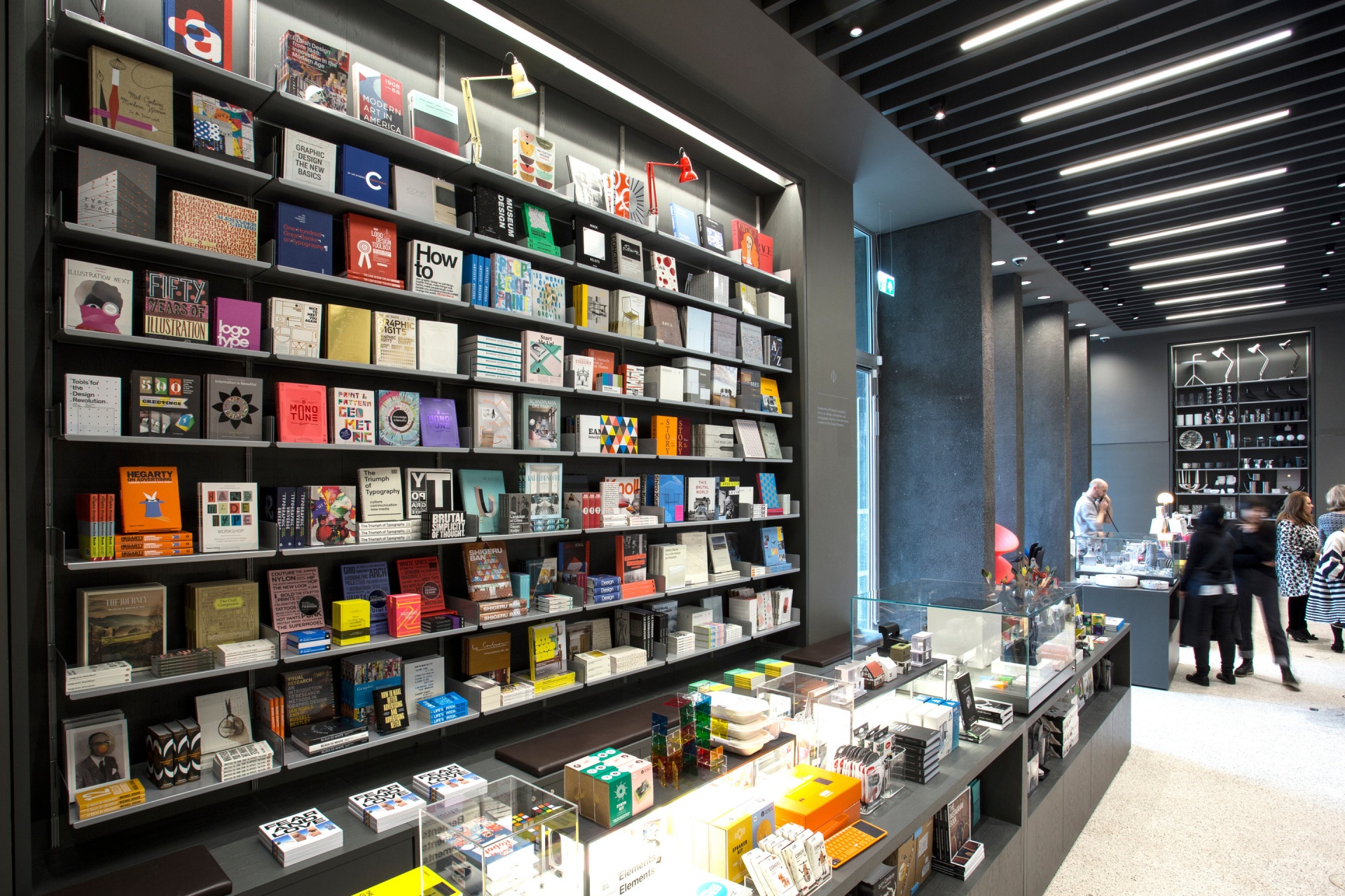 Museum library shelving, book retail display shelves in silver metal. Modern wall mounted bookshelves. Floor to ceiling. Modular Vitsœ 606 Universal Shelving System. Design Dieter Rams