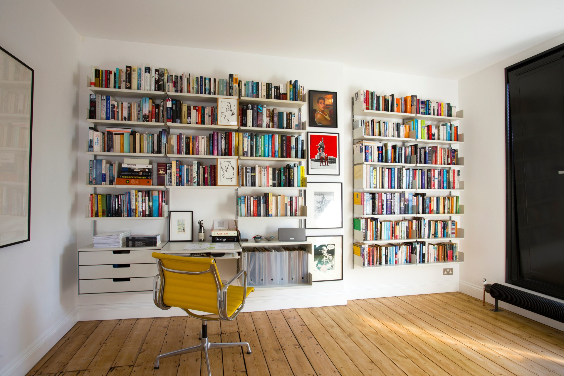 Modular shelving system with desk and strong shelves for large collection of books and box file storage. Above desk shelving unit in off-white, wall-mounted bookshelves for modern home office. Designer shelves, Dieter Rams. Vitsœ 606 Universal Shelving System.