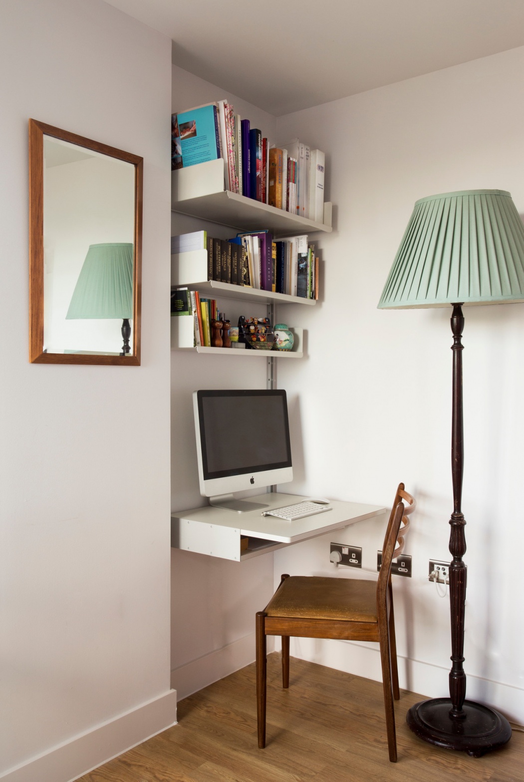 Modular shelving system with desk in alcove. Above desk shelving unit, wall-mounted bookshelf in off-white for modern home officein the living room. Designer shelves, Dieter Rams. Vitsœ 606 Universal Shelving System.