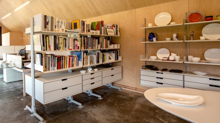 Free standing shelving system, wall mounted shelving with drawer cabinets. Vitsœ 606 in off-white displaying tableware ceramics for product design company Studio Levien.