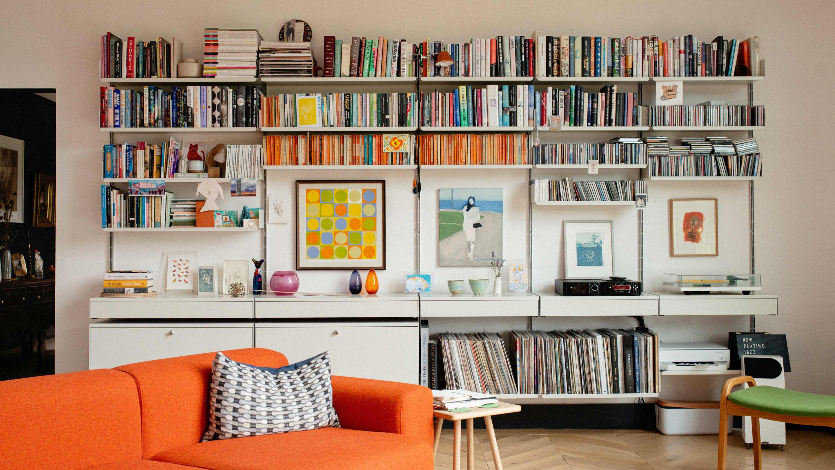 Modular wall-mounted shelving system for book with off-white shelves, cabinets and drawers.